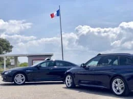 Deux voitures noires stationnées devant un bâtiment avec un drapeau français.