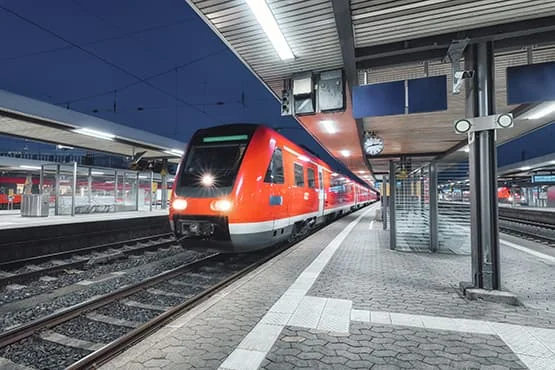 Train régional rouge et gris à quai dans une gare.